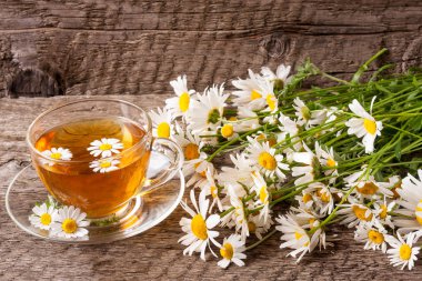 Eski ahşap zemin üzerine taze papatya çiçeği ile bitkisel çay