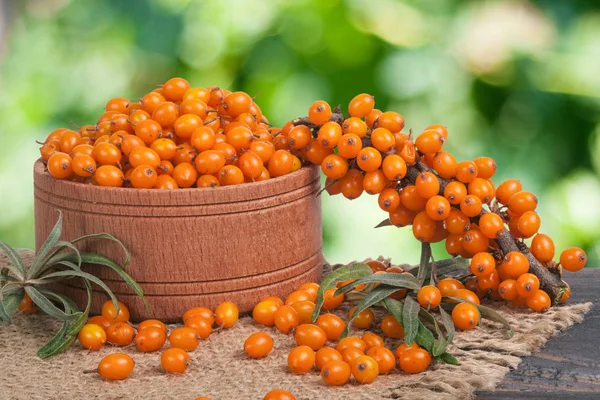 Sanddornbeeren in einer hölzernen Schüssel auf dem Tisch mit verschwommenem Gar — Stockfoto