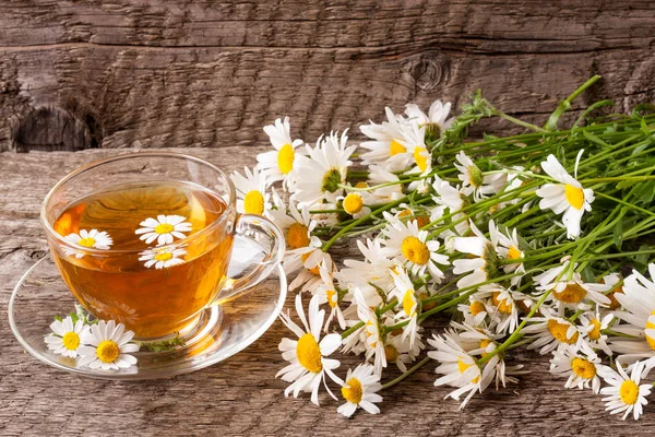 Eski ahşap zemin üzerine taze papatya çiçeği ile bitkisel çay