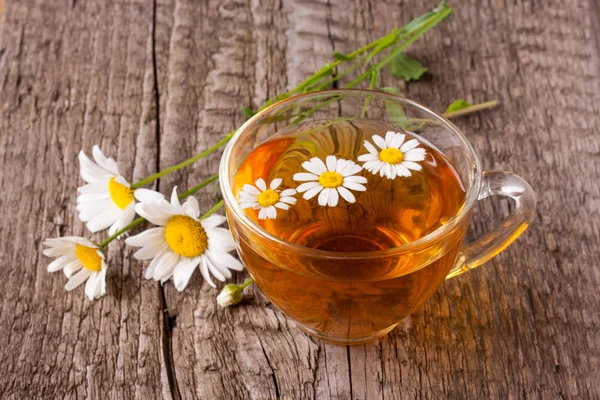 Eski ahşap zemin üzerine taze papatya çiçeği ile bitkisel çay