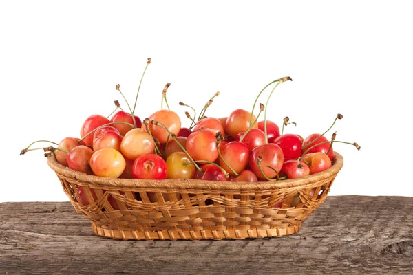 Gele kers in een rieten mand op een houten tafel met een witte achtergrond — Stockfoto