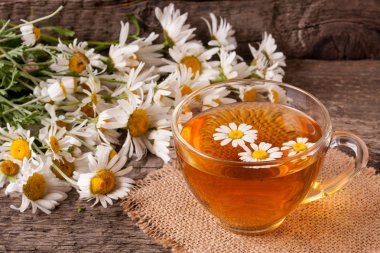 Eski ahşap zemin üzerine taze papatya çiçeği ile bitkisel çay