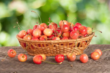 Bir bulanık ile ahşap bir masa üzerinde bir hasır sepet içinde sarı kiraz