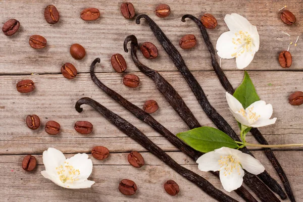 Vanilla tongkat dengan biji kopi dan bunga di belakang kayu tua — Stok Foto