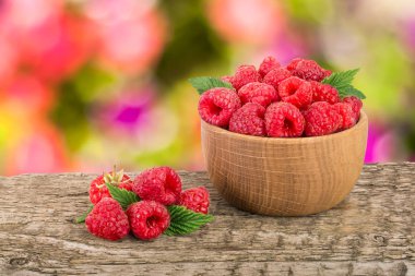 Ahududu bulanık bir bahçe arka plan ile tabloda bir ahşap kase