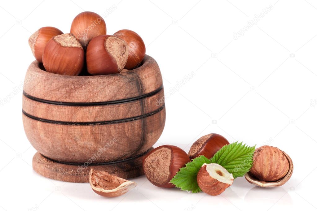 Hazelnuts with leaves in a wooden bowl isolated on white background