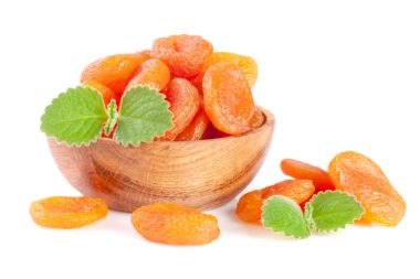 Nane yaprakları üzerinde WHI izole bir ahşap kase kuru kayısı