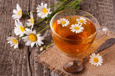 Eski ahşap zemin üzerine taze papatya çiçeği ile bitkisel çay