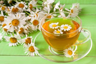 Yeşil ahşap zemin üzerine taze papatya çiçeği ile bitkisel çay