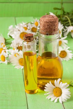 esans ve yeşil ahşap arka plan üzerinde taze papatya çiçeği ile şişe