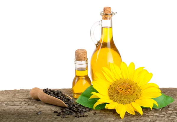 Solrosolja, frön och blomma på träbord med vit bakgrund — Stockfoto