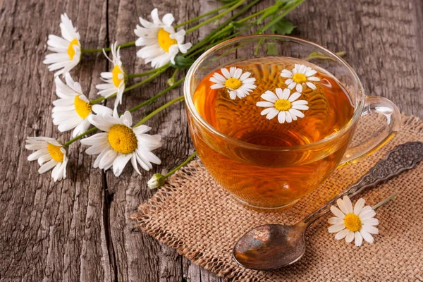 Eski ahşap zemin üzerine taze papatya çiçeği ile bitkisel çay