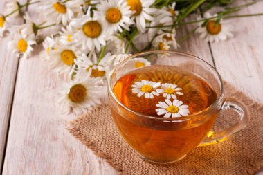 Beyaz ahşap zemin üzerinde taze papatya çiçeği ile bitkisel çay