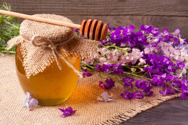 Kavanoz bal ile kır çiçekleri koyu ahşap arka plan üzerinde