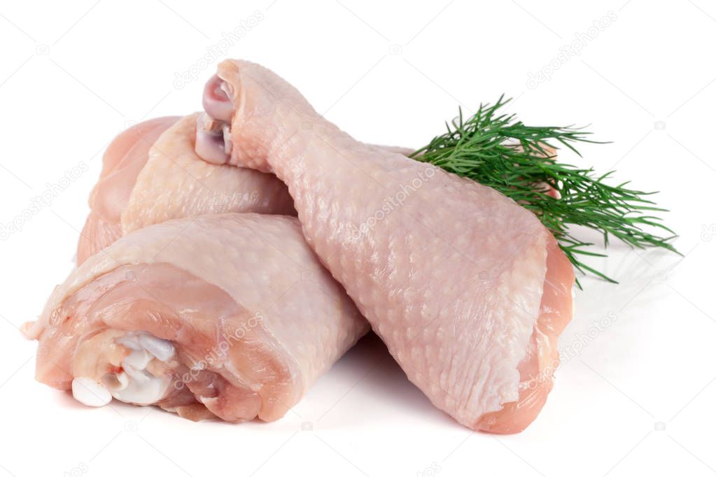 Three raw chicken drumsticks with a sprig of dill isolated on white background