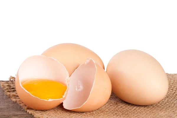 Uovo rotto con tuorlo e guscio d'uovo su un tavolo di legno con sfondo bianco — Foto Stock