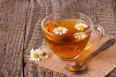 Eski ahşap zemin üzerine taze papatya çiçeği ile bitkisel çay