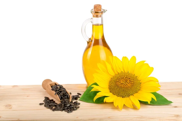 Óleo de girassol, sementes e flor em mesa de madeira com fundo branco — Fotografia de Stock