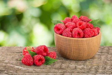 Ahududu bulanık bir bahçe arka plan ile tabloda bir ahşap kase