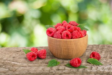 Ahududu bulanık bir bahçe arka plan ile tabloda bir ahşap kase