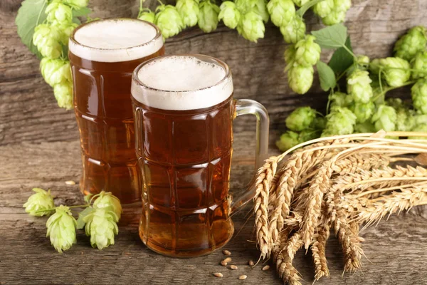 Склянка пінистого пива з шишками хмелю і пшениці на старому дерев'яному фоні — стокове фото