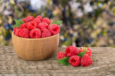 Ahududu bulanık bir bahçe arka plan ile tabloda bir ahşap kase