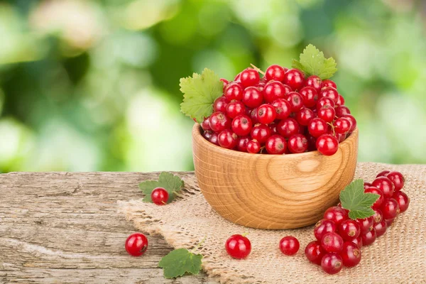 Frenk üzümü çilek bulanık Bahçe arka plan ile ahşap masa üzerinde ahşap kase