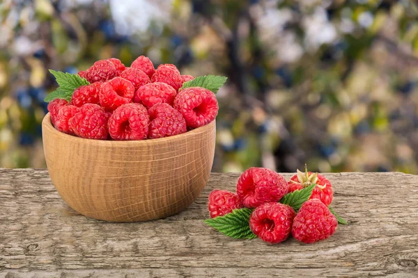 Ahududu bulanık bir bahçe arka plan ile tabloda bir ahşap kase