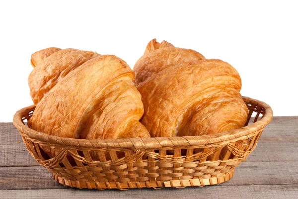 Croissant in cesto di vimini su un tavolo di legno con sfondo bianco — Foto Stock