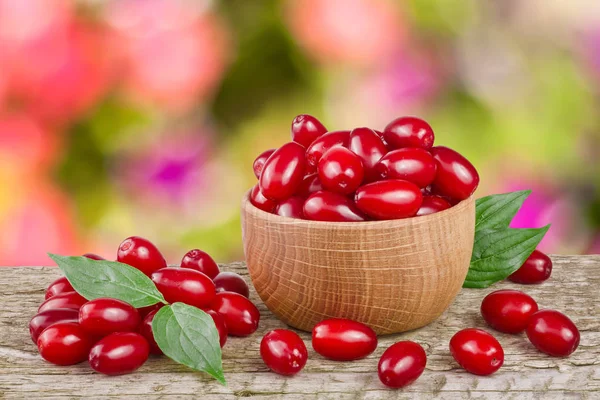 Kızılcık berry yaprak kase bulanık bir bahçe arka plan ile ahşap tablo