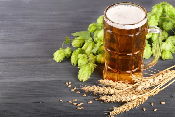 bardak köpüklü bira hop koniler ve buğday siyah ahşap zemin üzerine