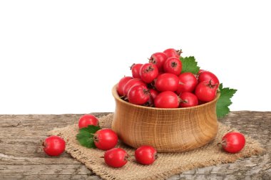 Hawthorn berry yaprak beyaz arka plan ile ahşap masa üzerinde bir kase ile