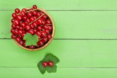 Frenk üzümü çilek yaprağı yeşil ahşap arka plan kopya alanı metni ile ahşap bir kase. Üstten Görünüm