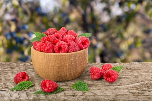 Ahududu bulanık bir bahçe arka plan ile tabloda bir ahşap kase