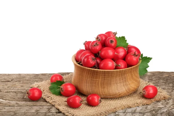Hawthorn berry yaprak beyaz arka plan ile ahşap masa üzerinde bir kase ile