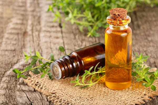 Botella de aceite esencial con tomillo de hierbas sobre un fondo de madera viejo — Foto de Stock