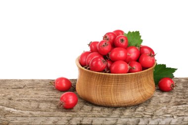 Hawthorn berry yaprak beyaz arka plan ile ahşap masa üzerinde bir kase ile
