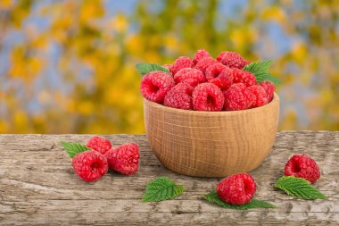 Ahududu bulanık bir bahçe arka plan ile tabloda bir ahşap kase