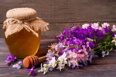 Kavanoz bal ile kır çiçekleri koyu ahşap arka plan üzerinde