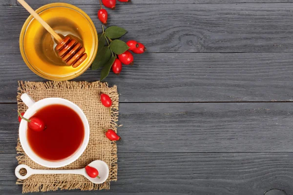 çay rose hips ve ballı kopya alanı metni siyah bir ahşap zemin üzerinde. Üstten Görünüm