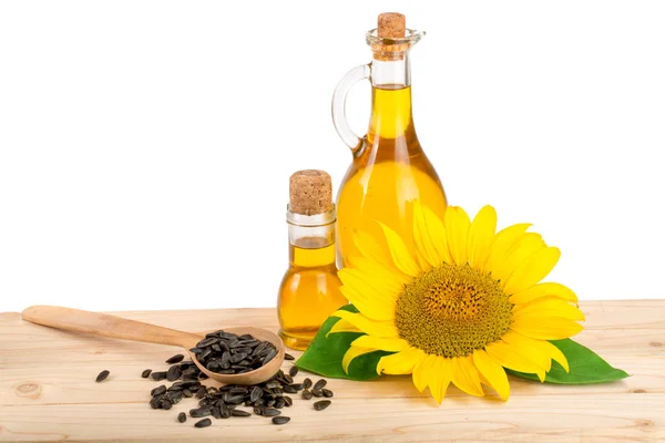 Olej słonecznikowy, nasion i kwiatów na drewniany stół z białym tłem — Zdjęcie stockowe