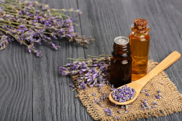 Aceite de hierbas y flores de lavanda sobre fondo de madera — Foto de Stock