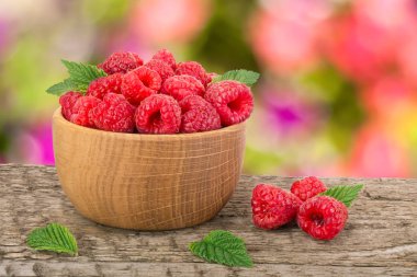 Ahududu bulanık bir bahçe arka plan ile tabloda bir ahşap kase