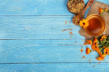 Taze ve kurutulmuş çiçekler, metniniz için kopya alanı mavi ahşap zemin üzerine Calendula çay. Üstten Görünüm