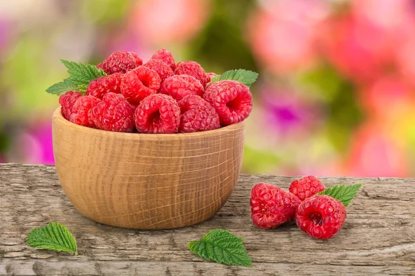 Ahududu bulanık bir bahçe arka plan ile tabloda bir ahşap kase