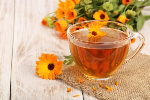 Calendula çay beyaz ahşap zemin üzerinde taze çiçekler ile