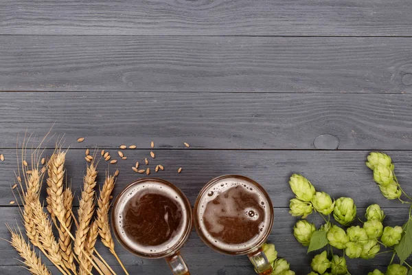 Склянка пінистого пива з шишками хмелю та пшениці на чорному дерев'яному фоні. Вид зверху з пробілом для копіювання вашого тексту — стокове фото