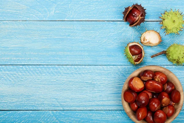 Castanha em tigela em fundo de madeira azul com espaço de cópia para o seu texto. Vista superior — Fotografia de Stock