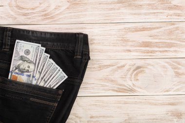 Amerikan Doları faturaları metniniz için kopya alanı ile beyaz ahşap zemin üzerinde kot pantolon cebinde. Üstten Görünüm