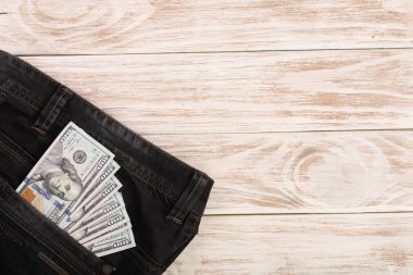Amerikan Doları faturaları metniniz için kopya alanı ile beyaz ahşap zemin üzerinde kot pantolon cebinde. Üstten Görünüm